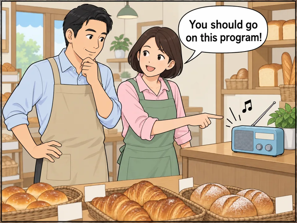 小さなパン屋の店内。カウンターの上のラジオから「Tell us about your shop!」という声と音符。太田さん（妻）がラジオを指さしながら、エプロン姿の夫に話しかけている。 吹き出し：You should go on this program!